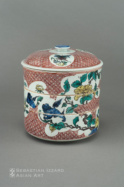 A PORCELAIN THREE-TIERED BOX WITH DOMED COVER  Hizen ware, early enamel type: porcelain with colored enamel decoration Edo period, Manji/early Kambun eras (1660−65)   H: 19 cm; D: 16.5 cm
