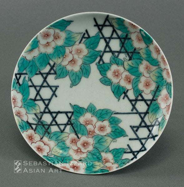 SMALL DISH (KOZARA) WITH DESIGN OF FLOWERING PRUNUS AND LATTICEWORK Hizen ware, Nabeshima type: porcelain with underglaze blue and colored enamels Edo period, circa 1650–60 15.1 cm diameter